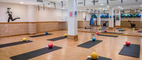 A fitness studio with exercise mats, balls, and a mirrored wall.