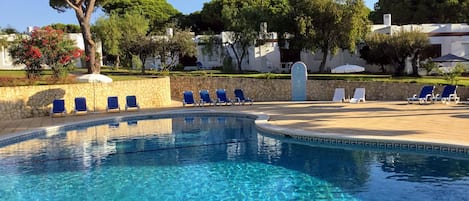 Una piscina al aire libre, sombrillas, tumbonas