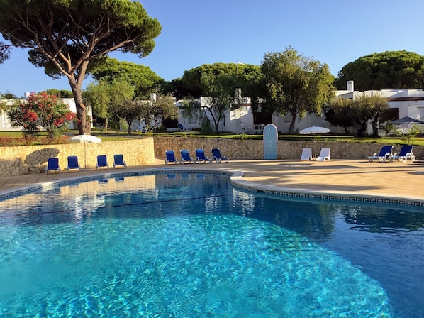 Una piscina al aire libre, sombrillas, tumbonas