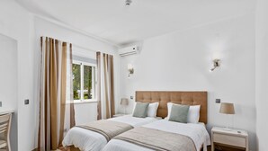 A bedroom with two beds, a desk, and a window with curtains. - Prado Villas (Loulé)