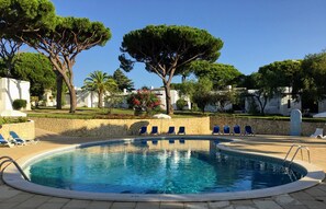 Una piscina al aire libre, sombrillas, sillones reclinables de piscina
