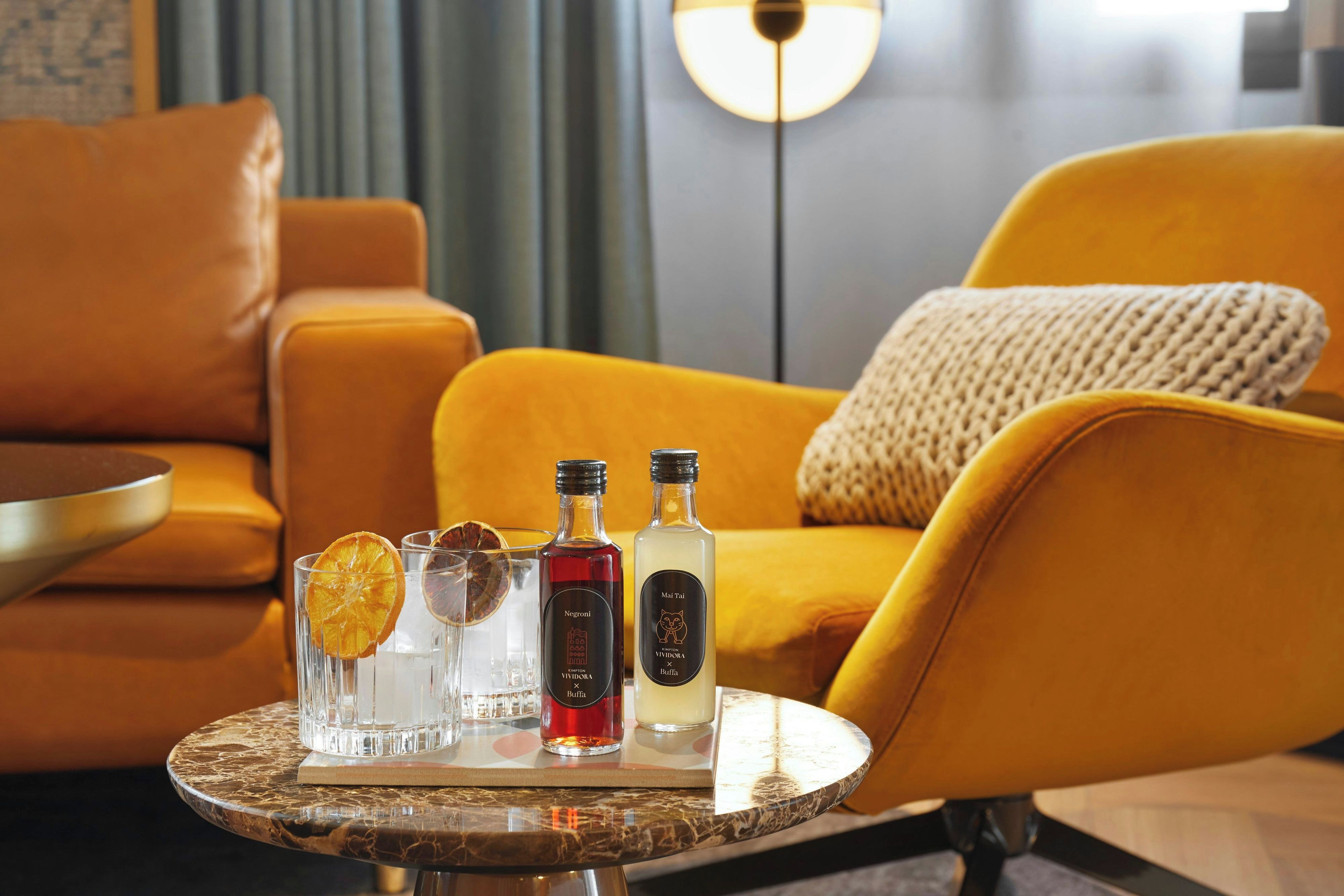 Una sala de estar moderna con un sofá amarillo, una mesa de centro redonda y dos botellas de licor.