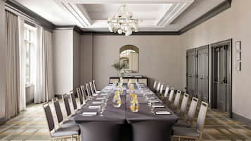 A conference room with a long table, chairs, a chandelier, and a mirror on the wall.