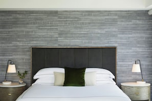 Een moderne slaapkamer met een groot bed, twee nachtkastjes en een structuurwand.