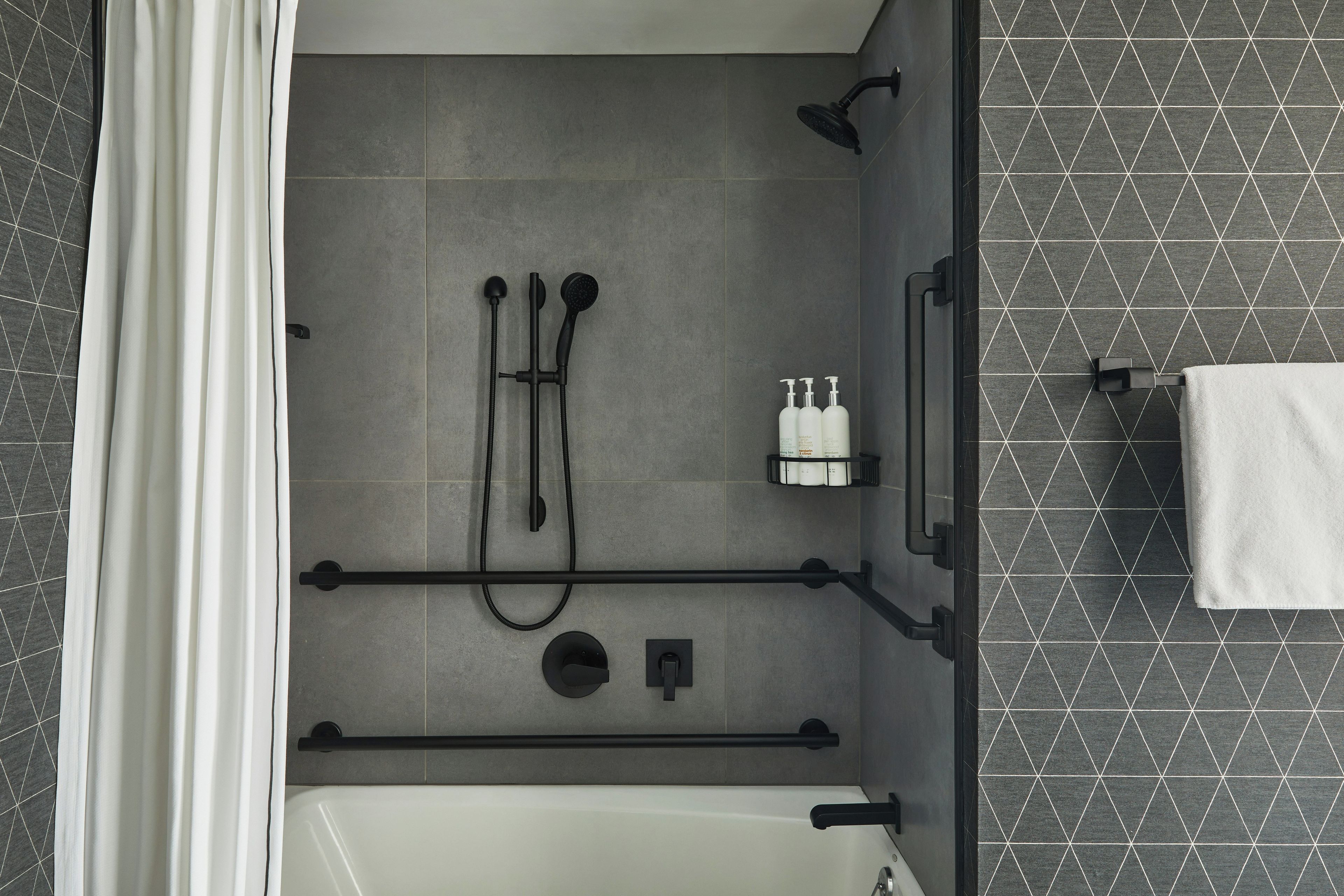 Un baño moderno con bañera, zona de ducha y un perchero para toallas.