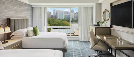 Une chambre d’hôtel avec deux lits, un bureau, une chaise, une télévision et une vue sur la ville.