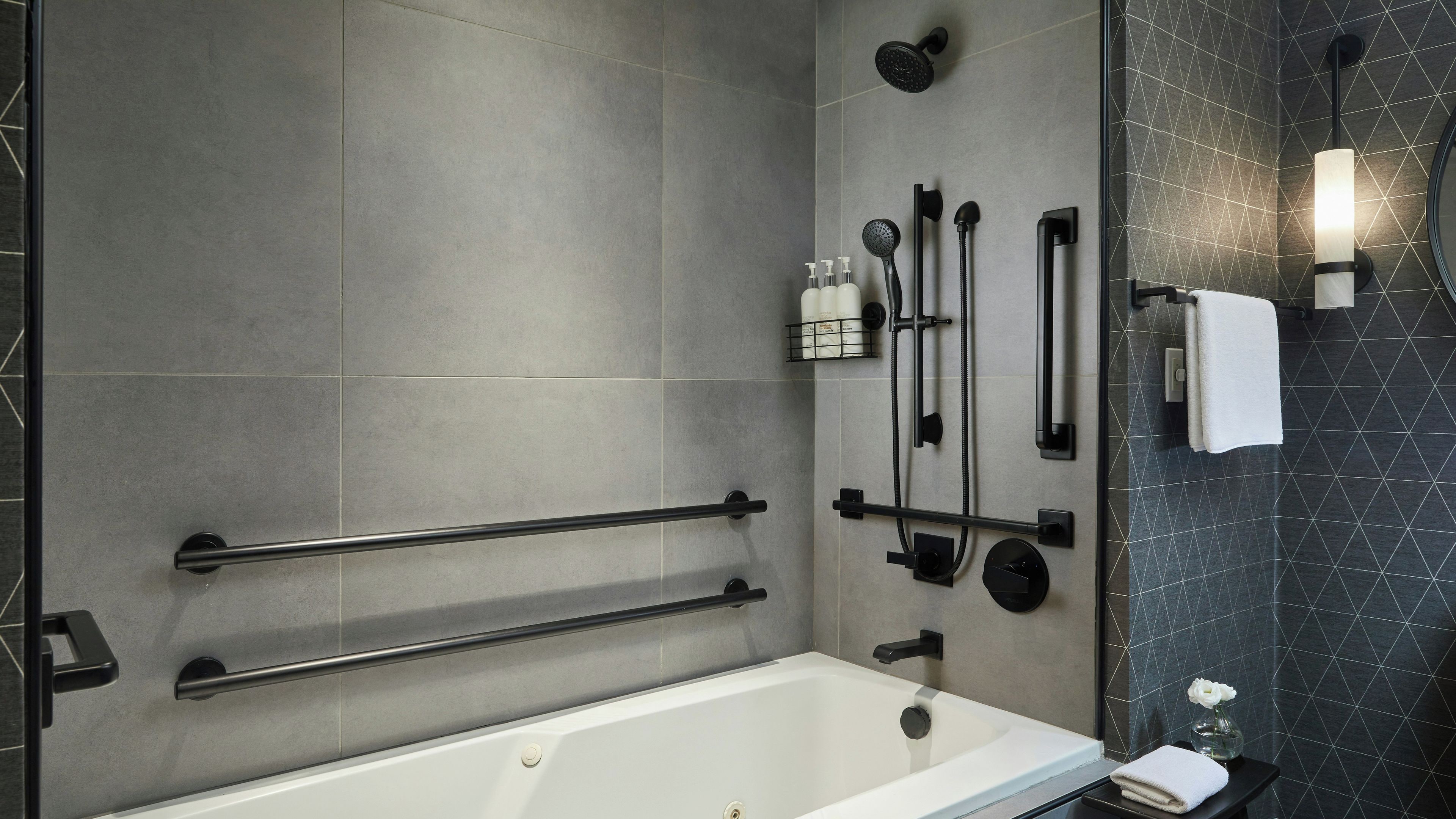A modern bathroom with a bathtub, towel rack, shower controls, and a glass shower enclosure.