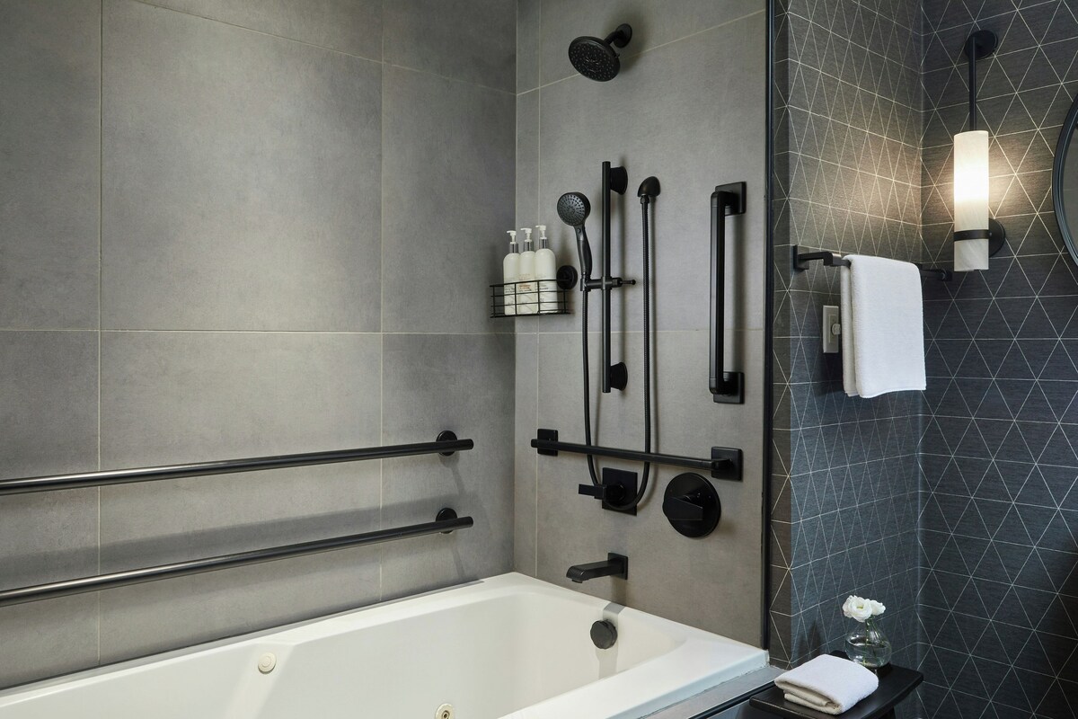 A modern bathroom with a bathtub, towel rack, shower controls, and a glass shower enclosure.