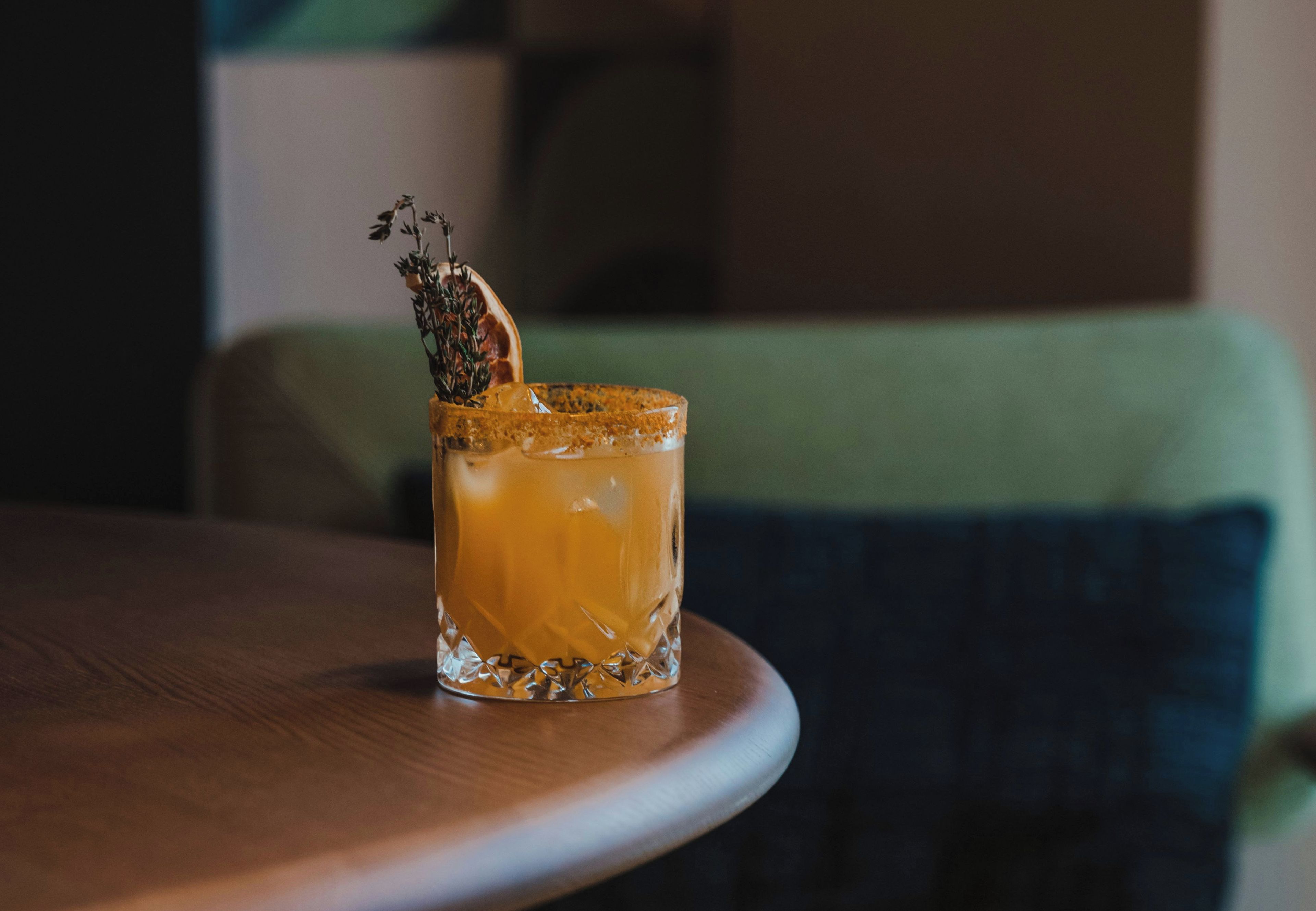 A glass with a drink on a wooden table.