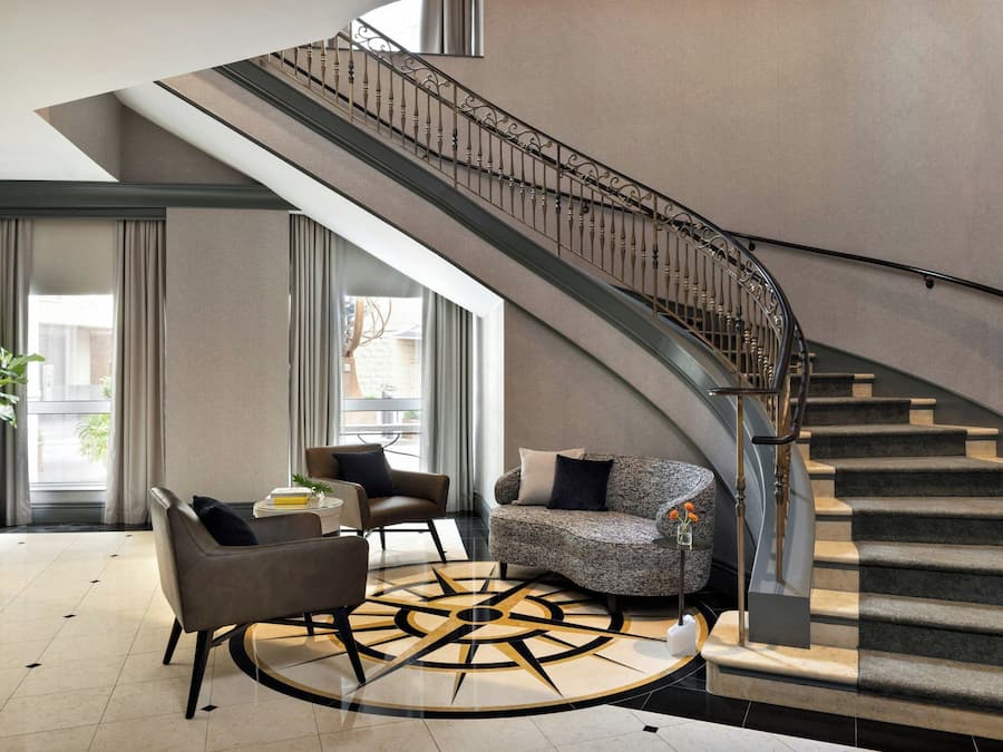 A modern interior with a curved staircase, a seating area with a round coffee table, and a large window providing natural light.