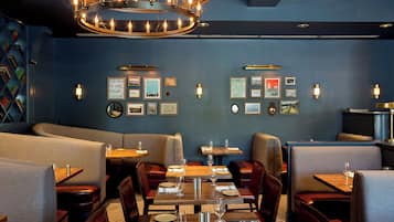 Un interior de restaurante con cabinas, mesas y una araña.