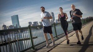 Three people jogging on a bridge with a city skyline in the background. - Kimpton Marlowe Hotel by IHG (Cambridge)