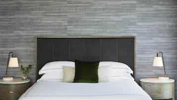 A neatly made bed with a dark headboard, two bedside tables with lamps, and a textured wall.