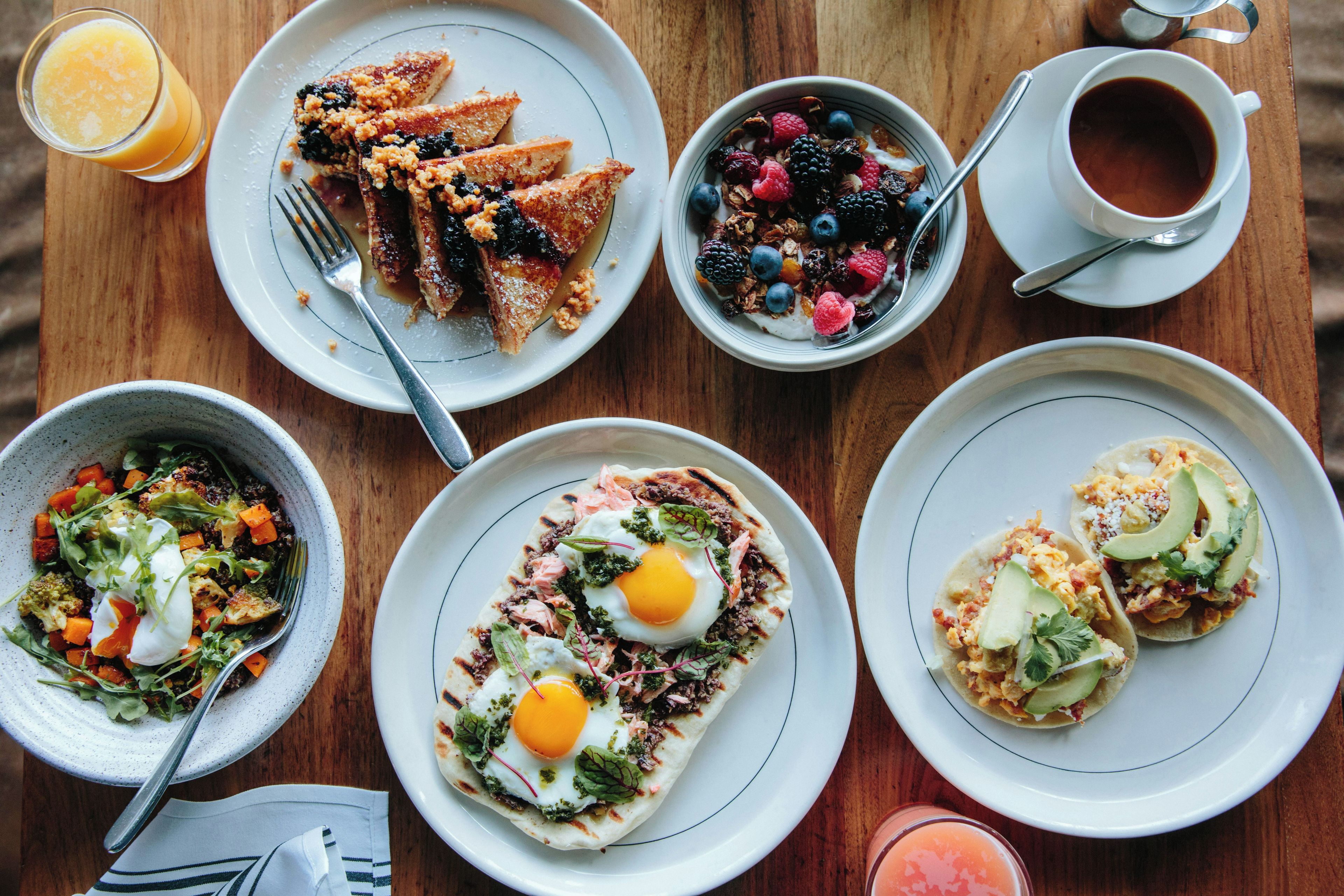 A breakfast setting with various dishes including toast, fruit, eggs, and a salad.