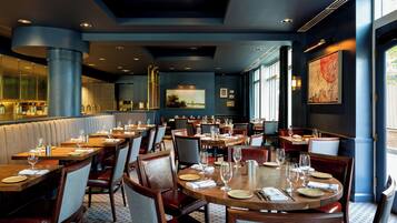 A restaurant interior with multiple dining tables, chairs, and a bar area.