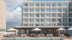 A hotel with a swimming pool, multiple balconies, and sun loungers.