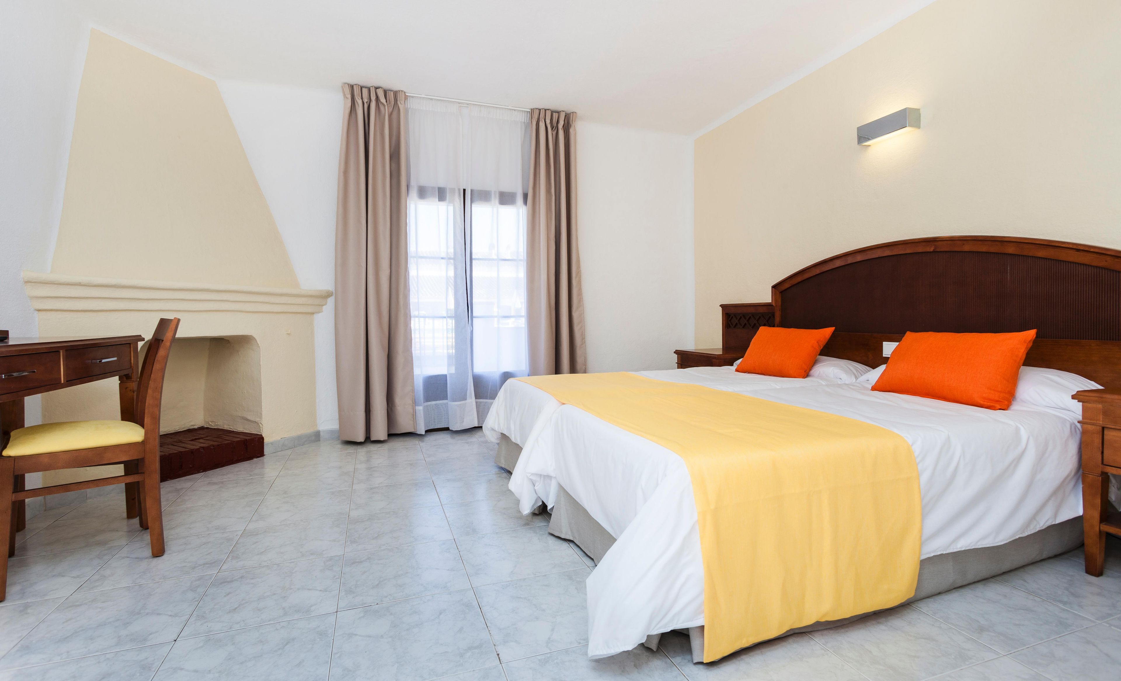 A hotel room with a bed, a desk, and a chair.