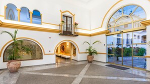 Un vestíbulo amplio con techo alto, un área de estar central y ventanas grandes que ofrecen vistas del exterior.