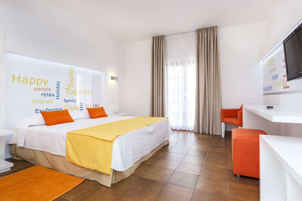 Une chambre d’hôtel avec un lit, un bureau, une chaise et un téléviseur.
