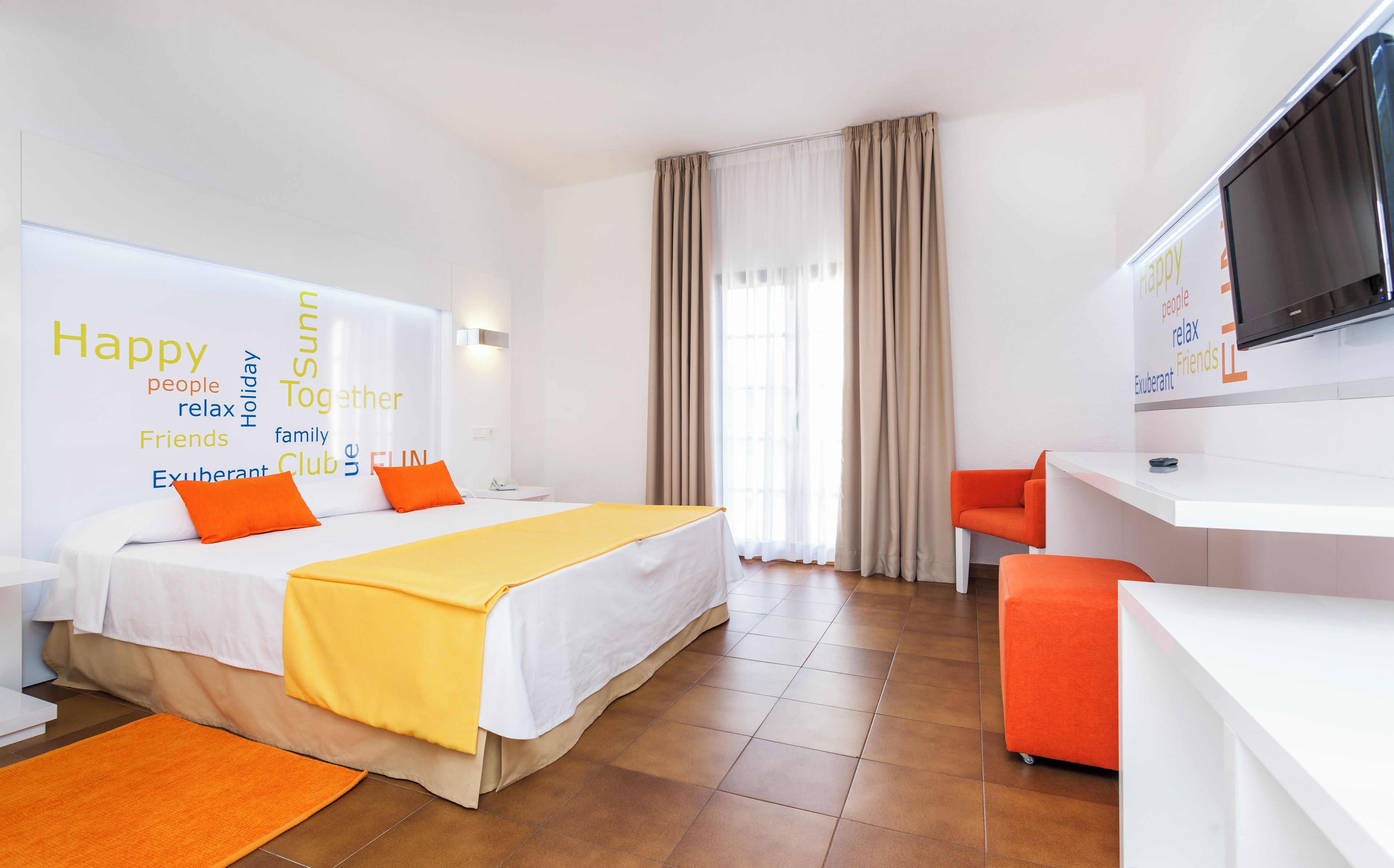 Una habitación de hotel con una cama, un escritorio, una silla y un televisor.