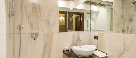 A modern bathroom with a marble vanity, a large mirror, and a shower enclosure.