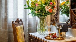 Una mesa con un arreglo floral, una copa de vino y una bandeja con fresas.
