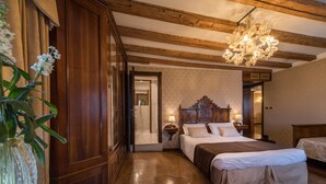 Un dormitorio con una cama grande, cabecera de madera, mesitas de noche, una araña y un armario de madera.