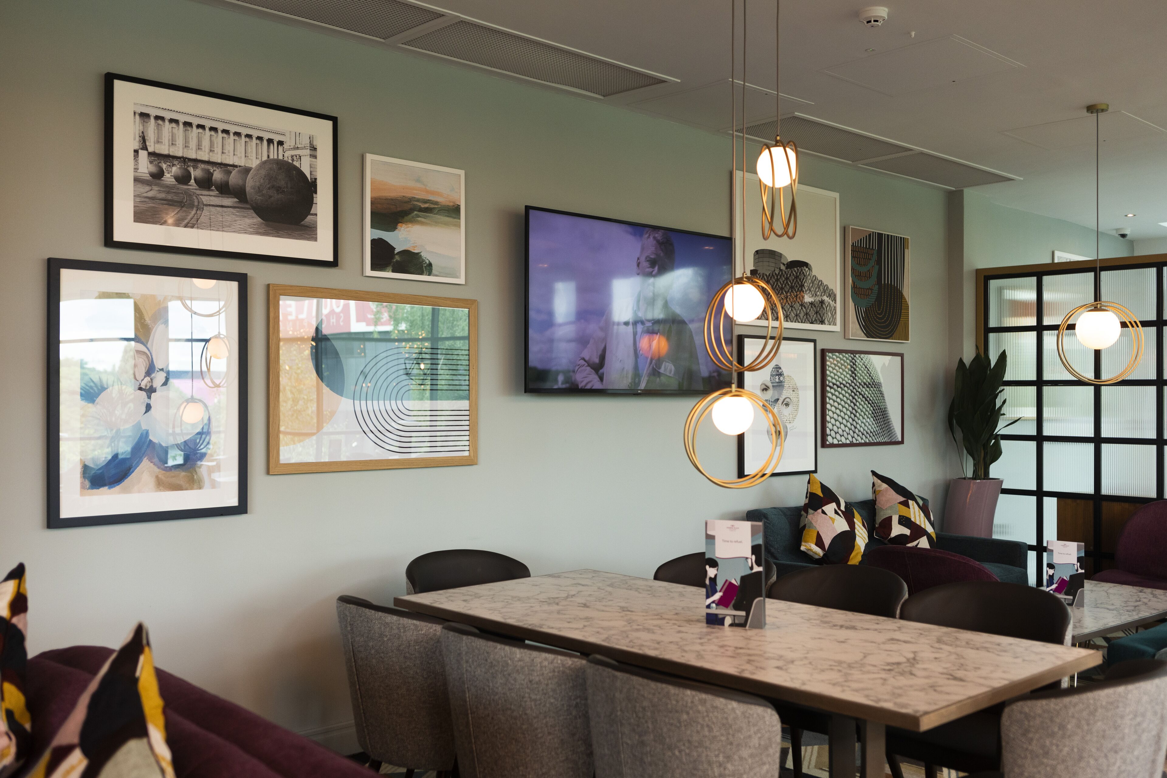 A modern conference room with a marble table, comfortable seating, and various framed artworks on the walls.