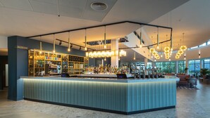 A modern bar area with a central island, pendant lighting, and a view of the outdoors through large windows. - Crowne Plaza Birmingham NEC by IHG (Birmingham)