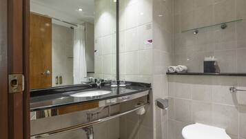 A modern bathroom with a double sink, a glass shower enclosure, and a toilet.