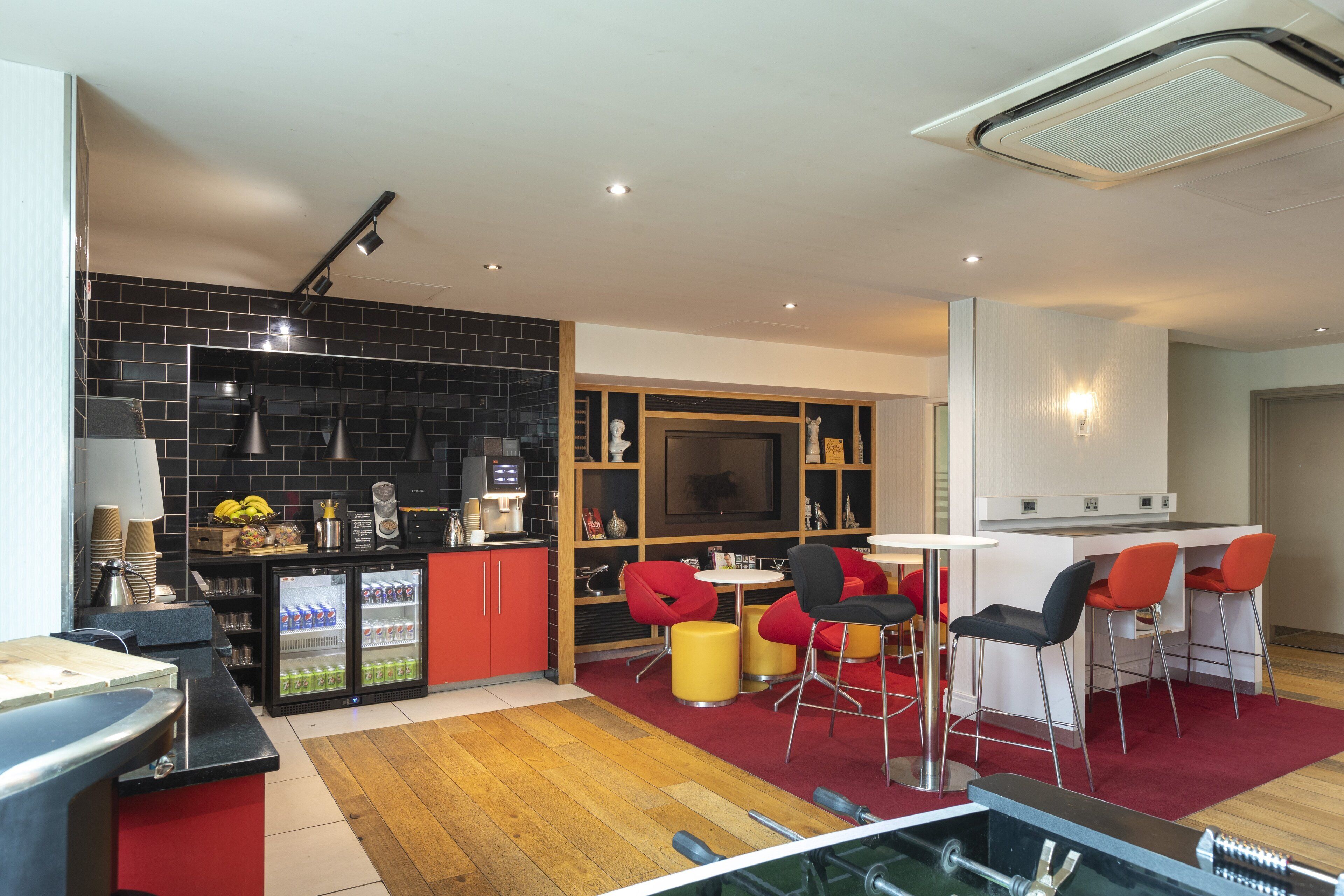 A modern kitchen with a black tiled backsplash, a built-in refrigerator, and a dining area with red and black chairs.