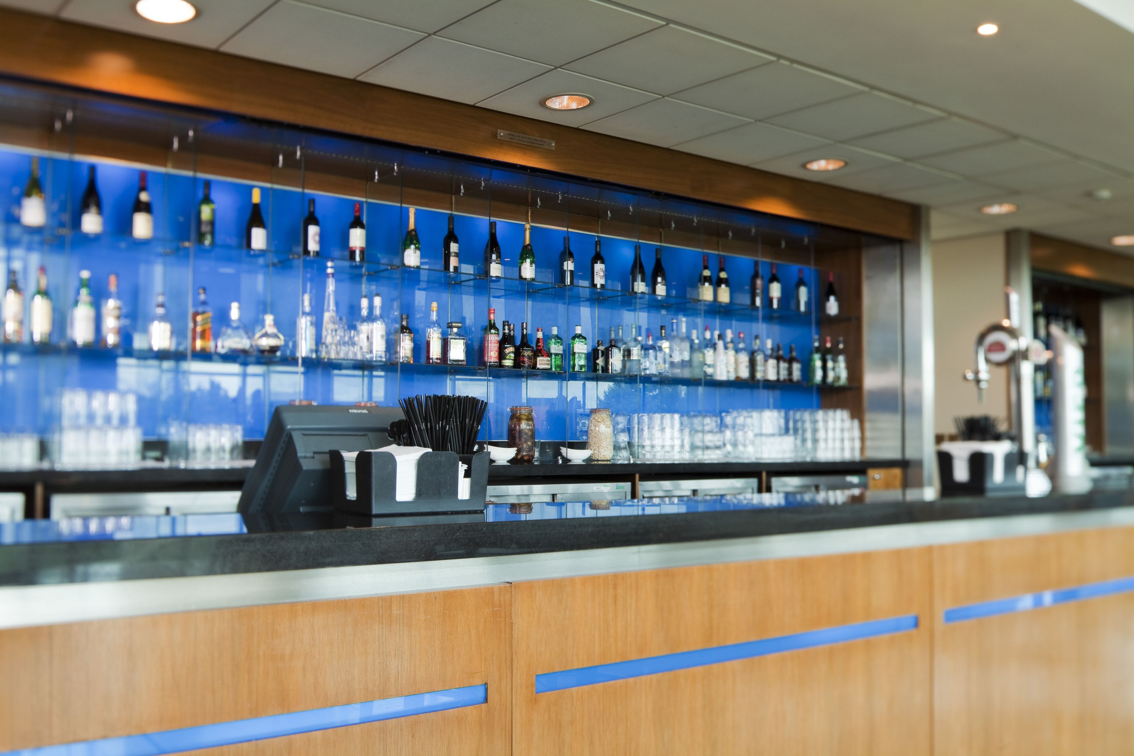 A bar area with shelves of bottles and a cash register.