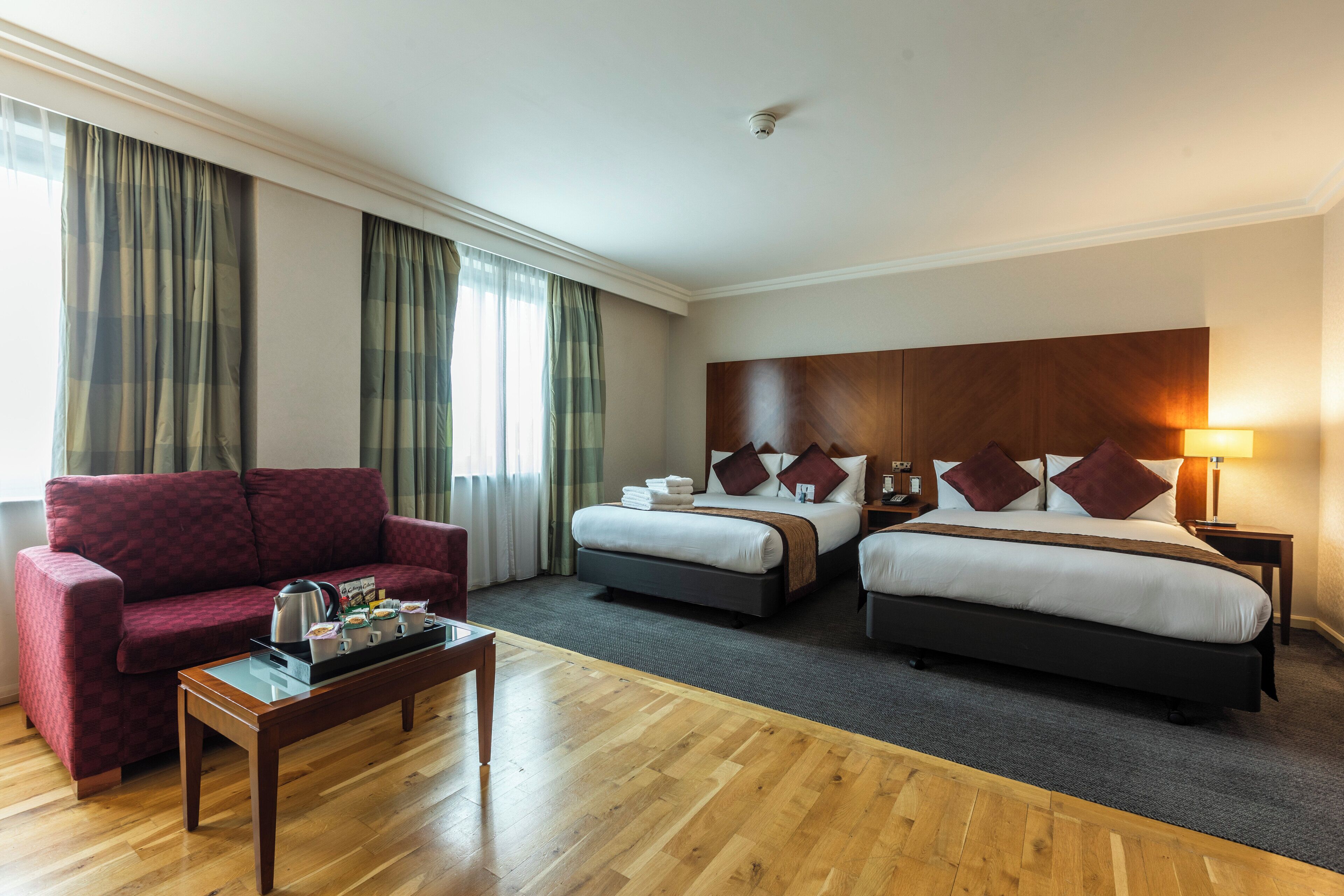 A hotel room with a large bed, a smaller bed, a sofa, and a coffee table.