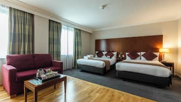 A hotel room with a large bed, a smaller bed, a sofa, and a coffee table.