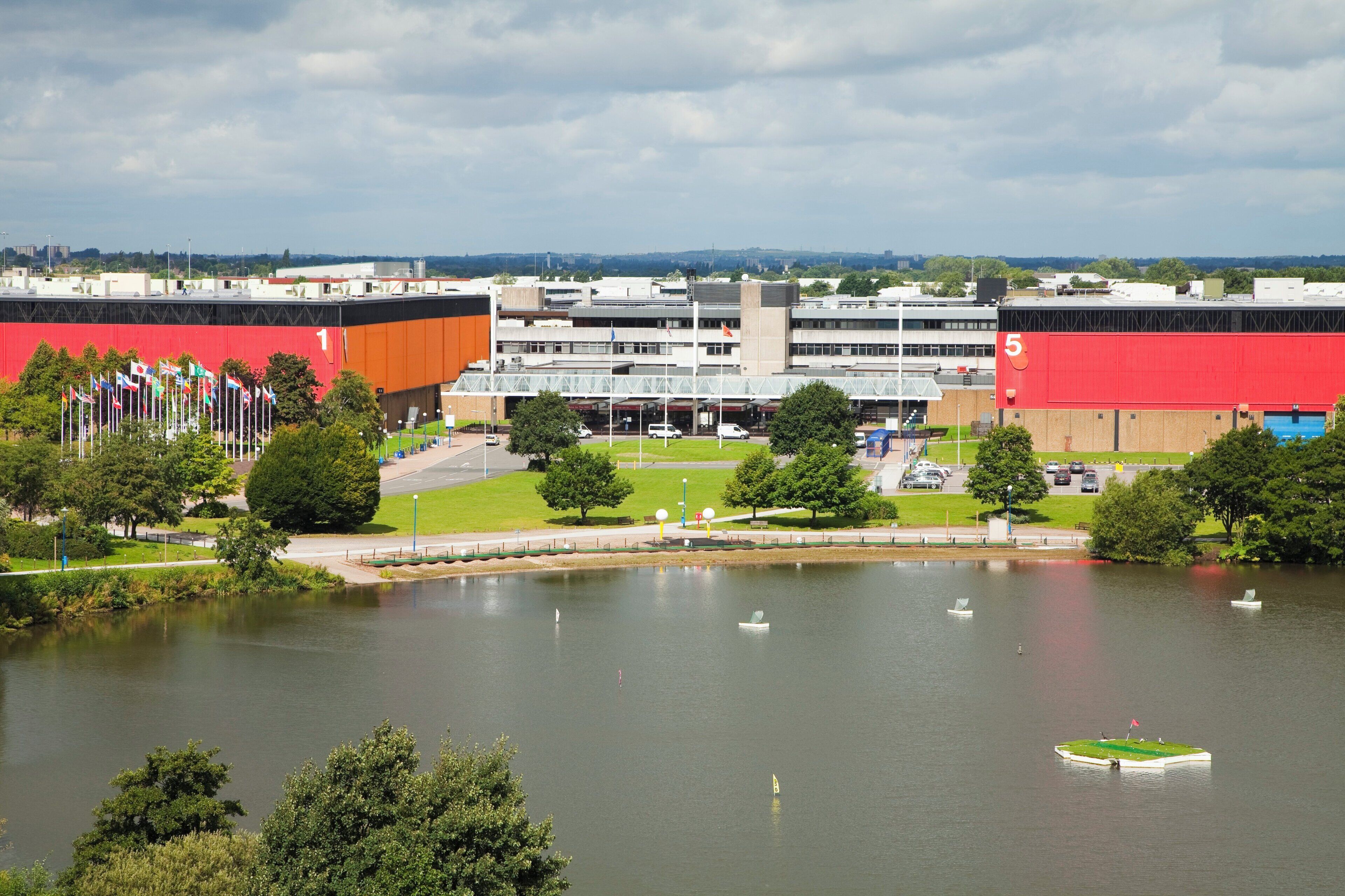 A large building with multiple floors and a red facade, surrounded by a body of water with several boats.