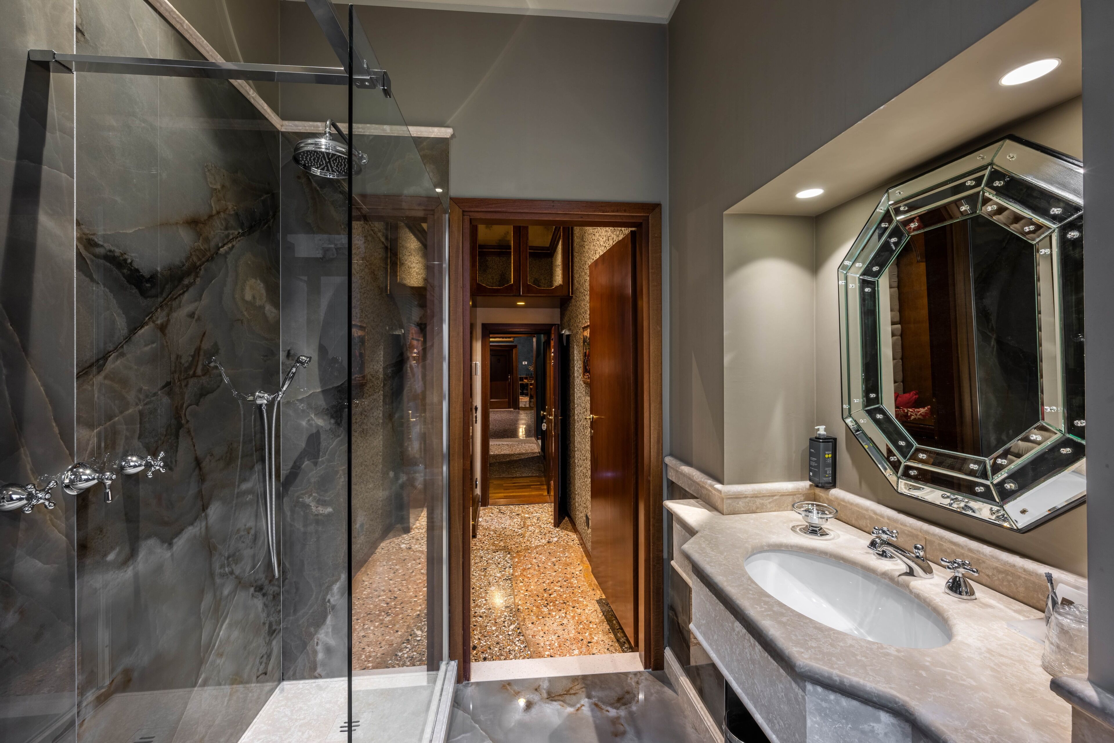 A modern bathroom with a glass-enclosed shower, a large mirror, and a dual sink vanity.