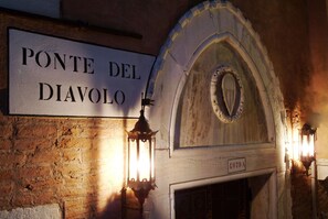 Un letrero que dice "PONTE DEL DIAVOLO" sobre un arco de piedra con una chimenea abajo.