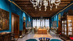 A room with a wooden ceiling, a chandelier, a sofa, and a table with a vase. - Hotel Palazzo Priuli (Venice)