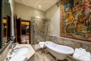 Un baño lujoso con una bañera grande, cabina de ducha con paredes de vidrio y suelo de mármol.