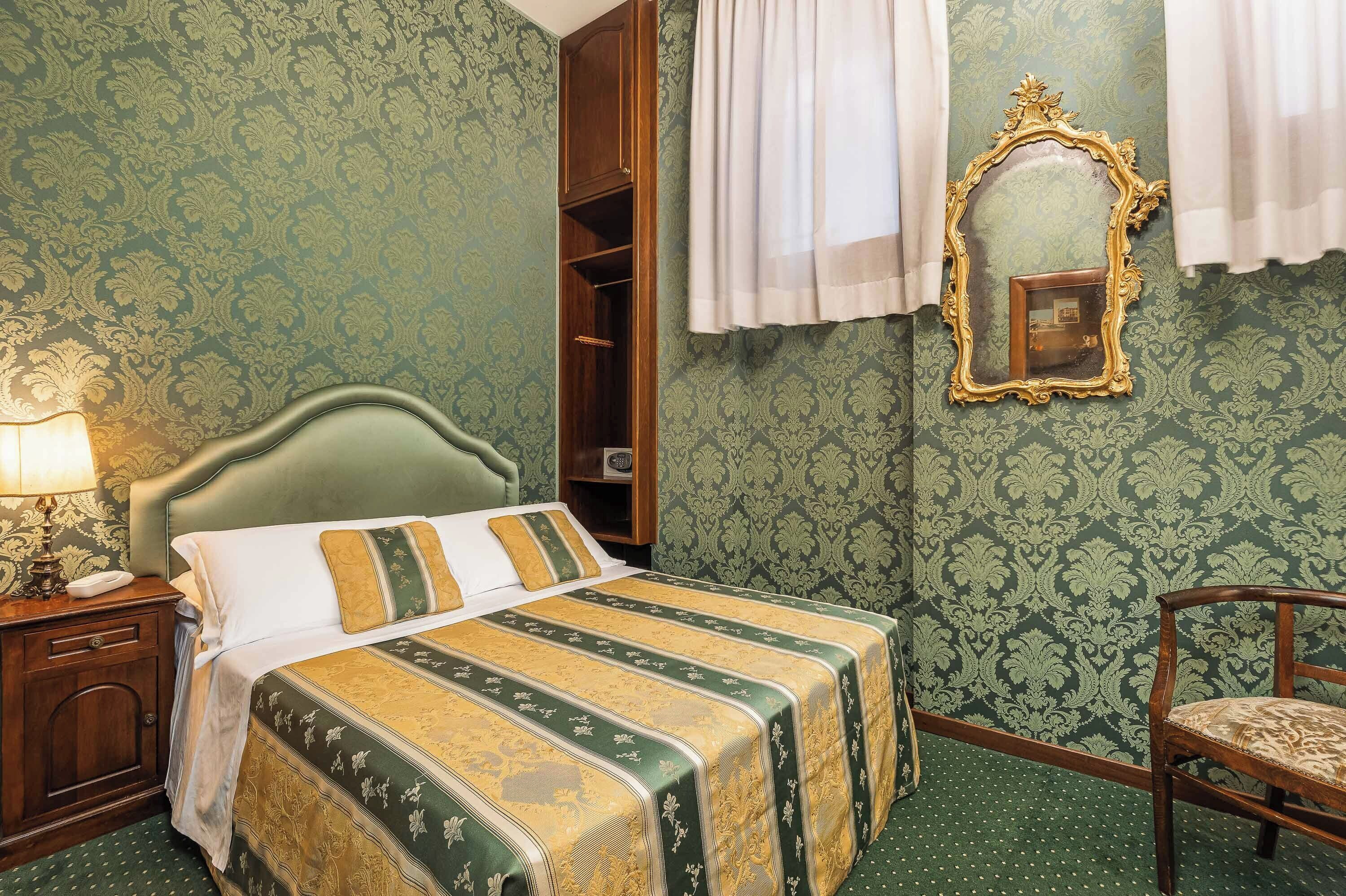 Una habitación con una cama, una mesita de noche, un espejo y una silla.