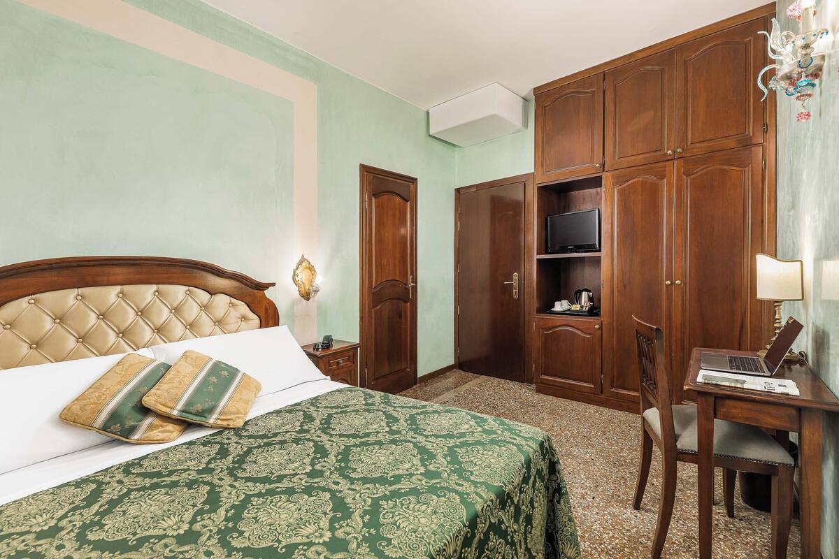 Un dormitorio con cama, escritorio y armario.