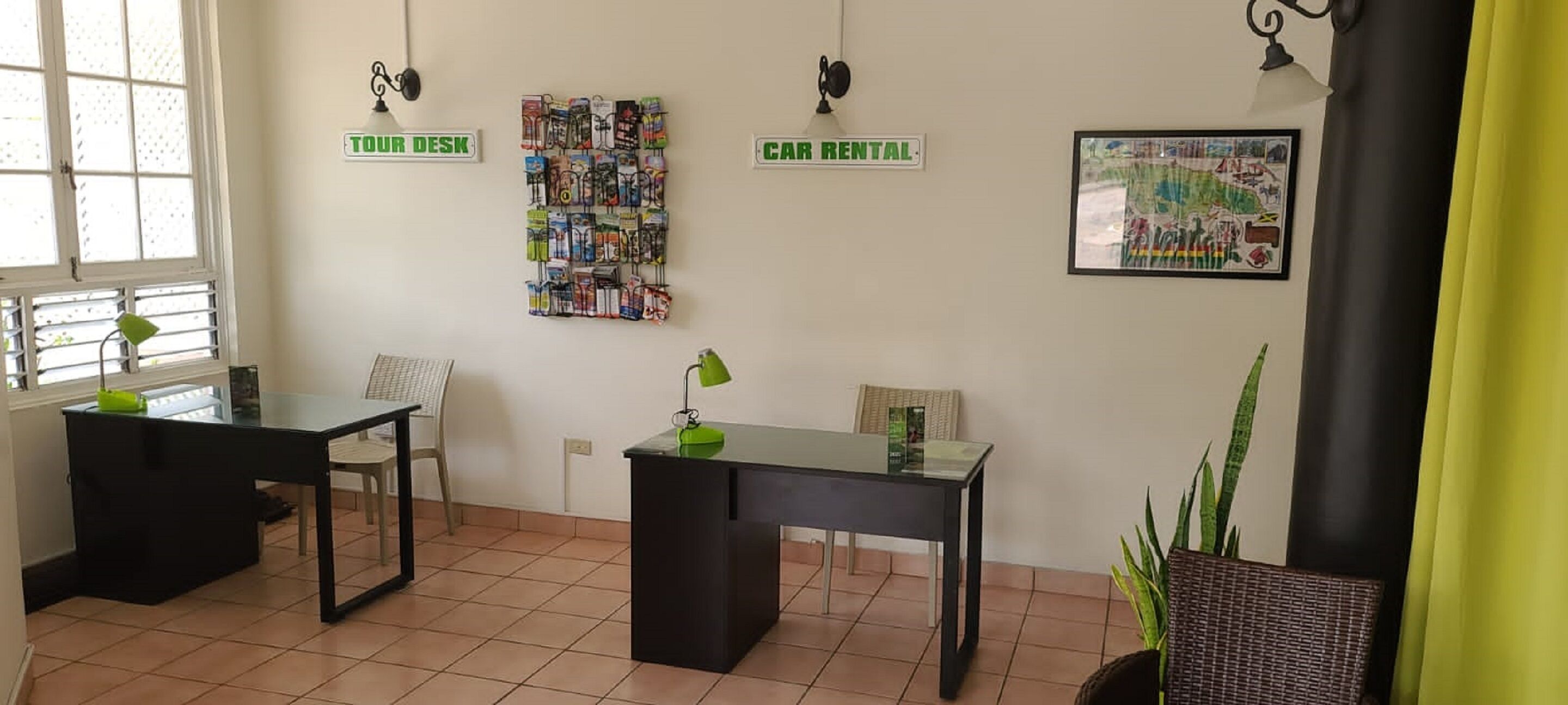 A reception area with two desks, a car rental sign, and a map on the wall.