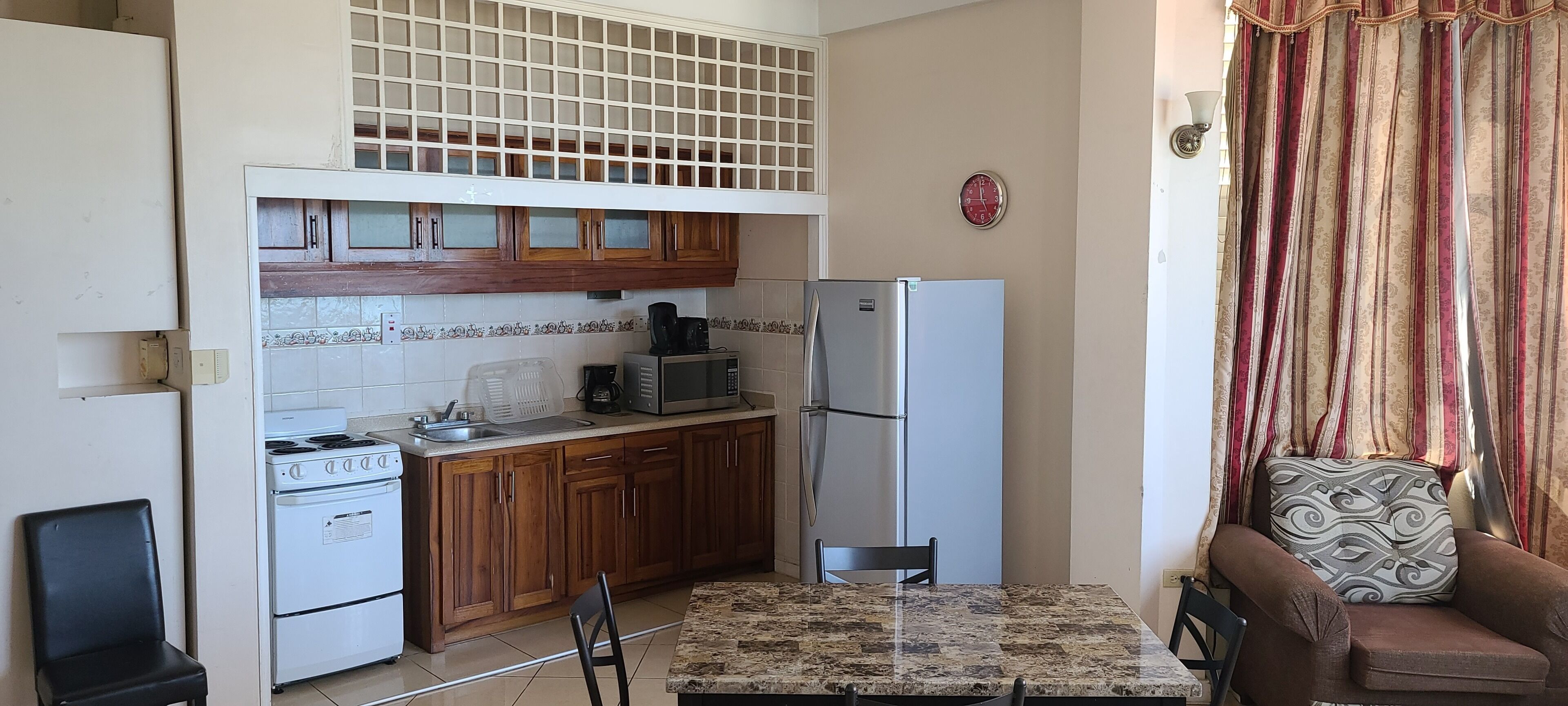 A compact kitchen with wooden cabinets, a refrigerator, a microwave, and a stove.