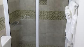 A bathroom with a glass-enclosed shower, a toilet, and a towel rack.