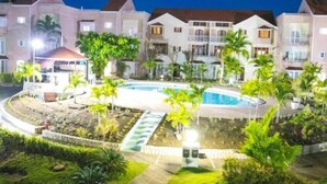 A hotel with multiple floors, a swimming pool, and palm trees.