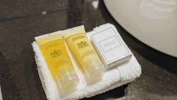A set of toiletries on a white towel, including a shower cap and two bottles of conditioner.