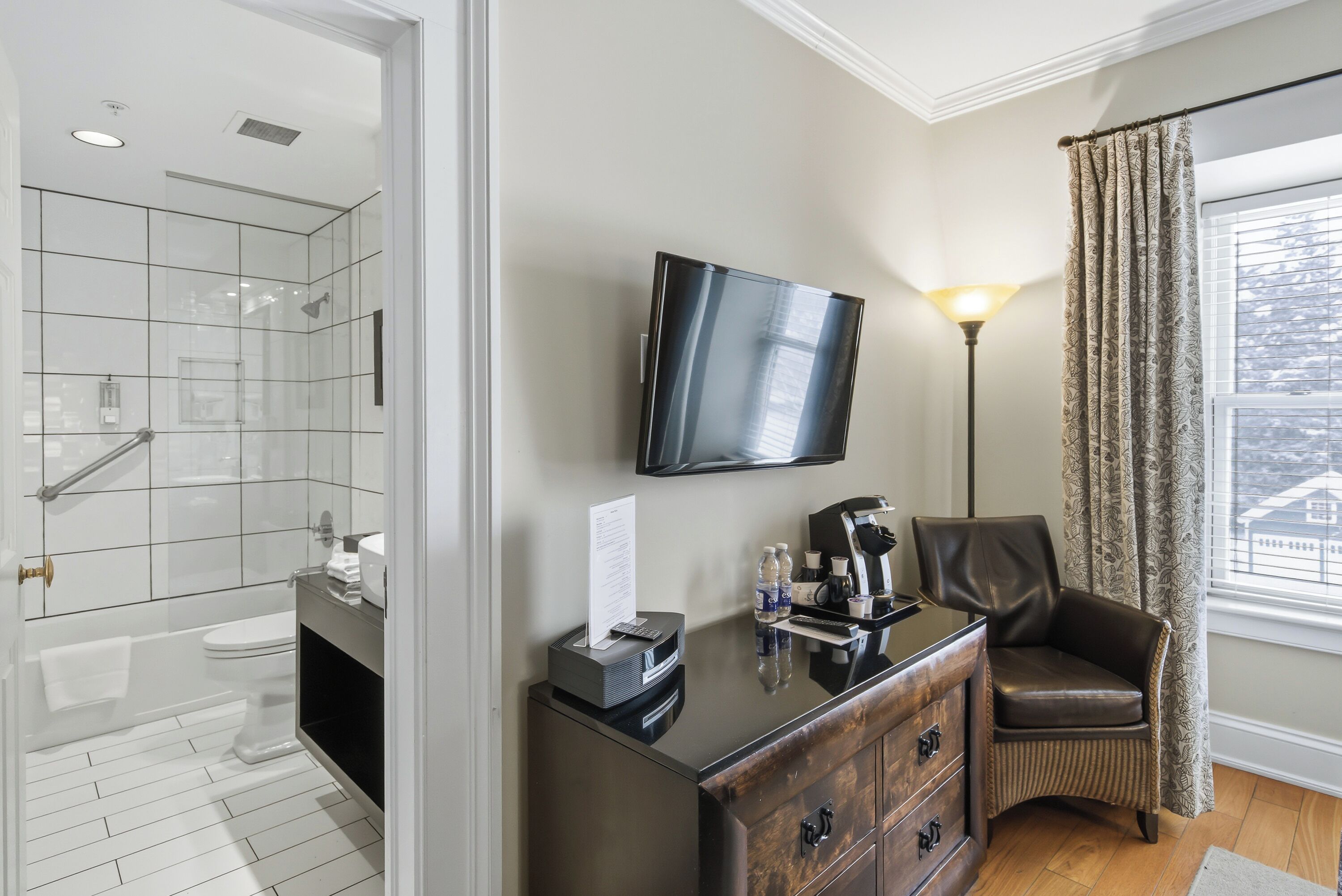 A modern bathroom with a glass shower, a toilet, a vanity with a mirror, and a flat-screen TV mounted on the wall.