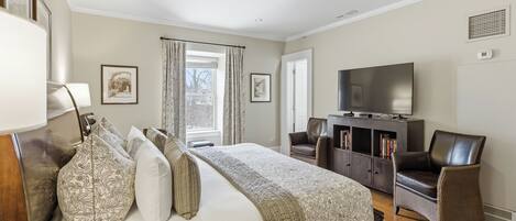 Quarto com cama, TV, escrivaninha e cadeira.