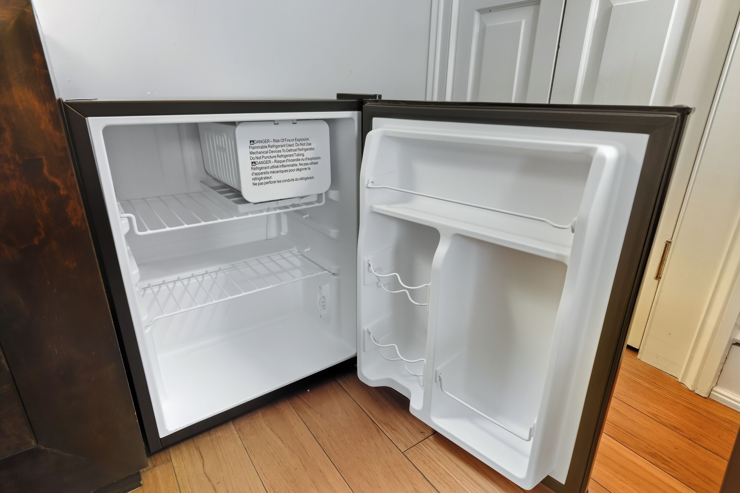 An open refrigerator with a warning label, a shelf, and a door handle.