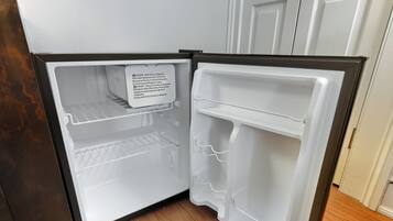 An open refrigerator with a warning label, a shelf, and a door handle.